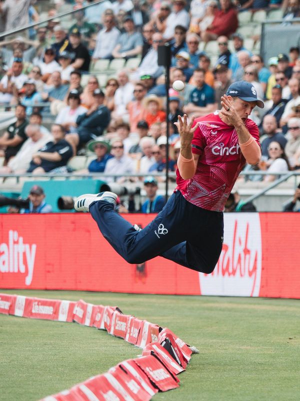 Cricket fielder leaping to take a catch