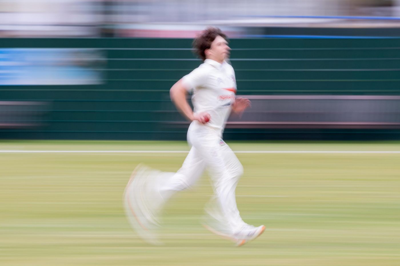 Cricketer in whites running on the outfield