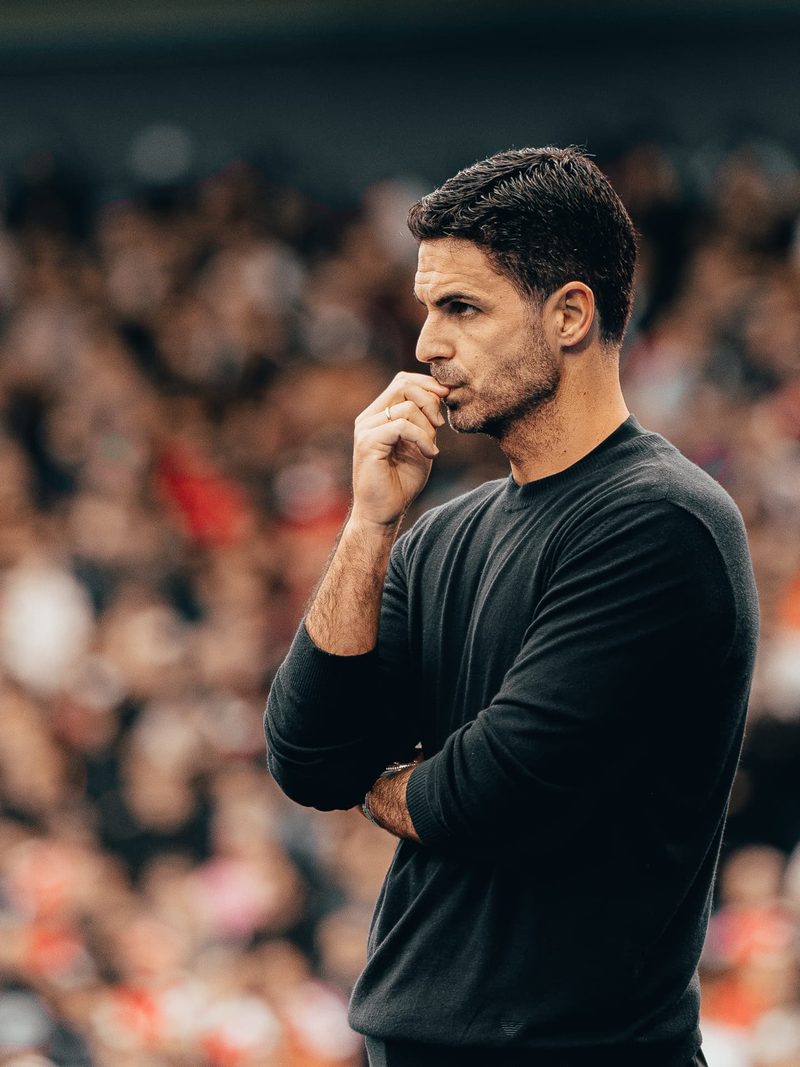 Football manager in black watching from the touchline