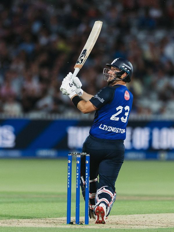 Cricket batsman playing a shot under lights