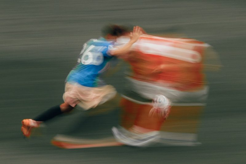 Footballers colliding in a tackle, panned motion blur