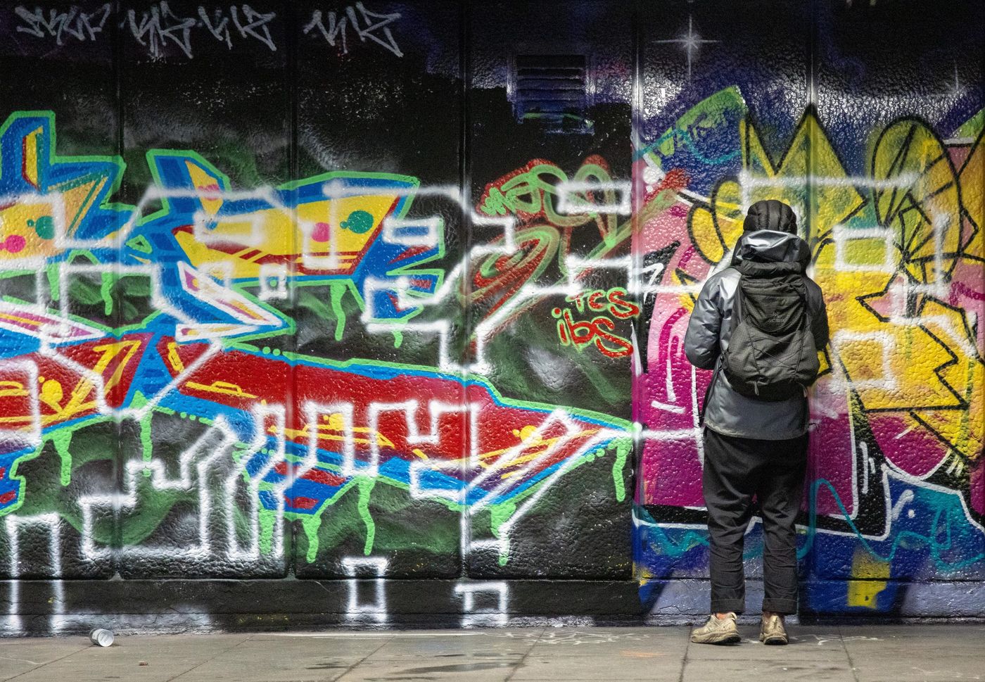 Person photographing a graffiti-covered wall