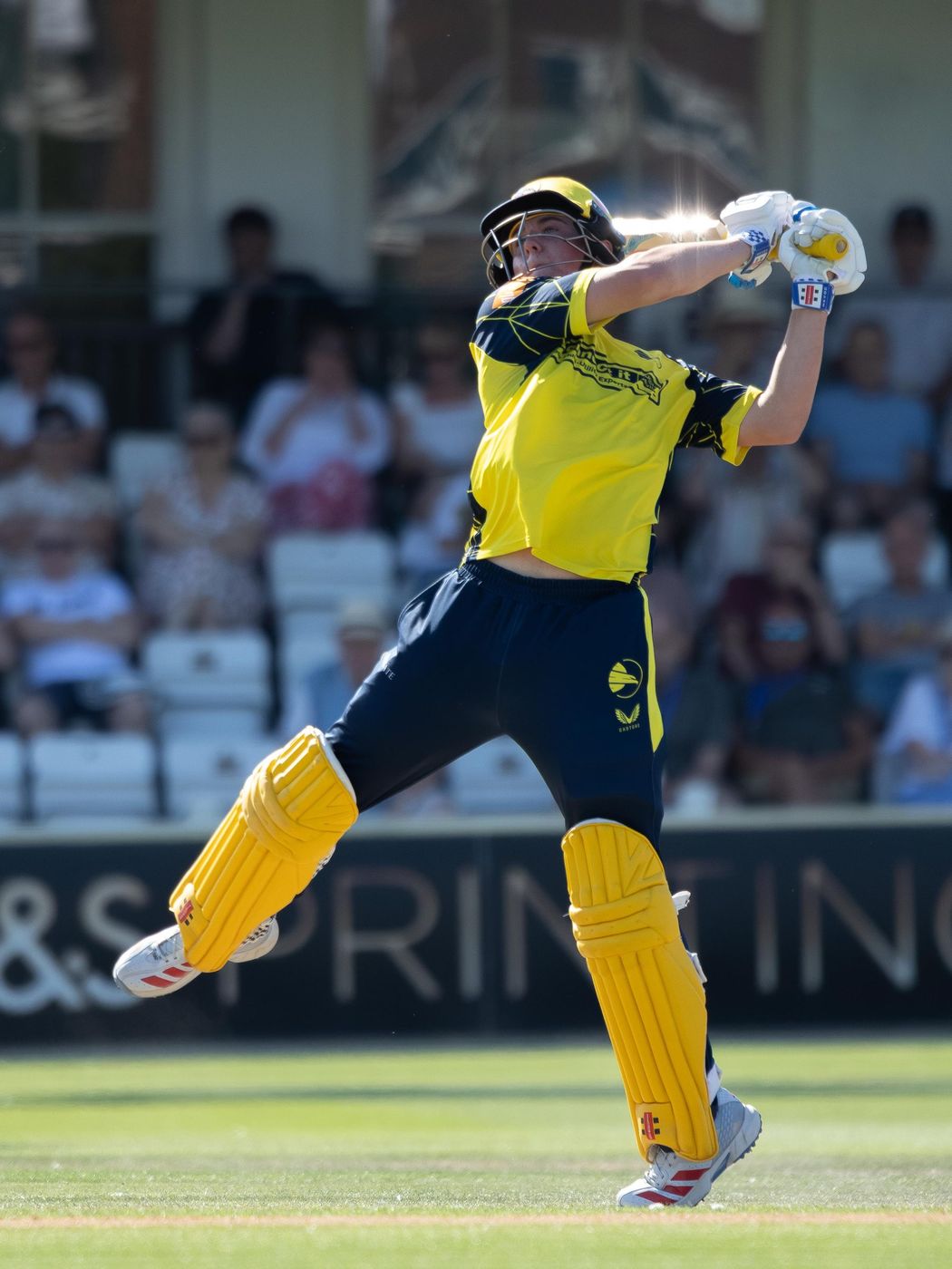 Cricket batsman in yellow playing a shot