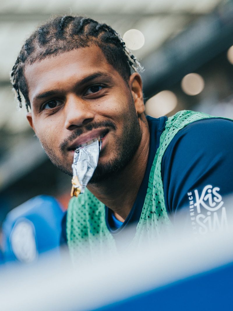 Footballer with braids biting a snack wrapper, close-up