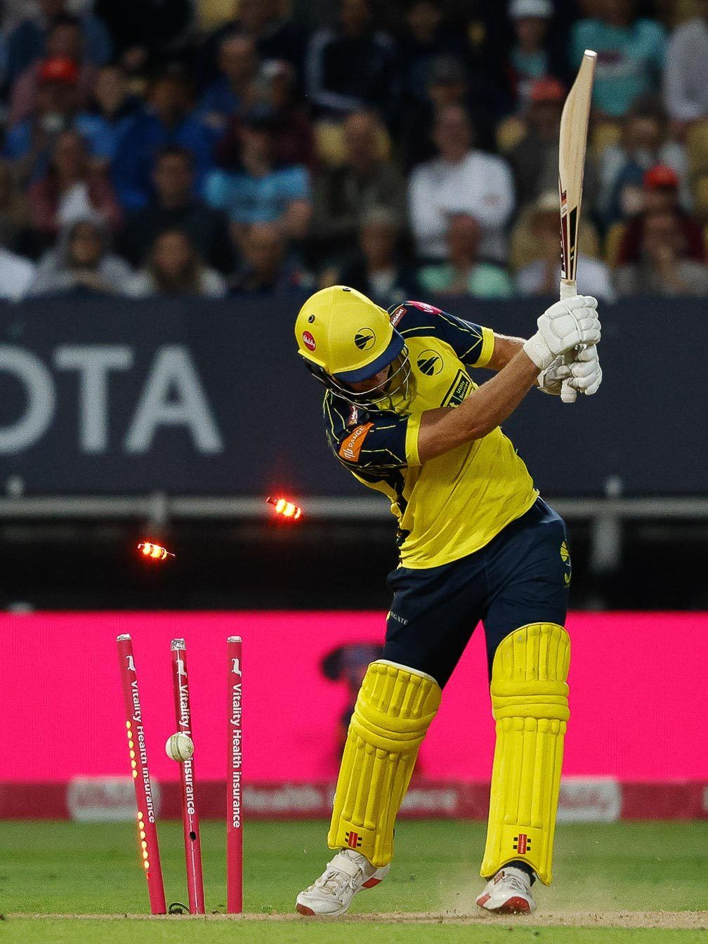 Cricket batsman bowled as the bails fly