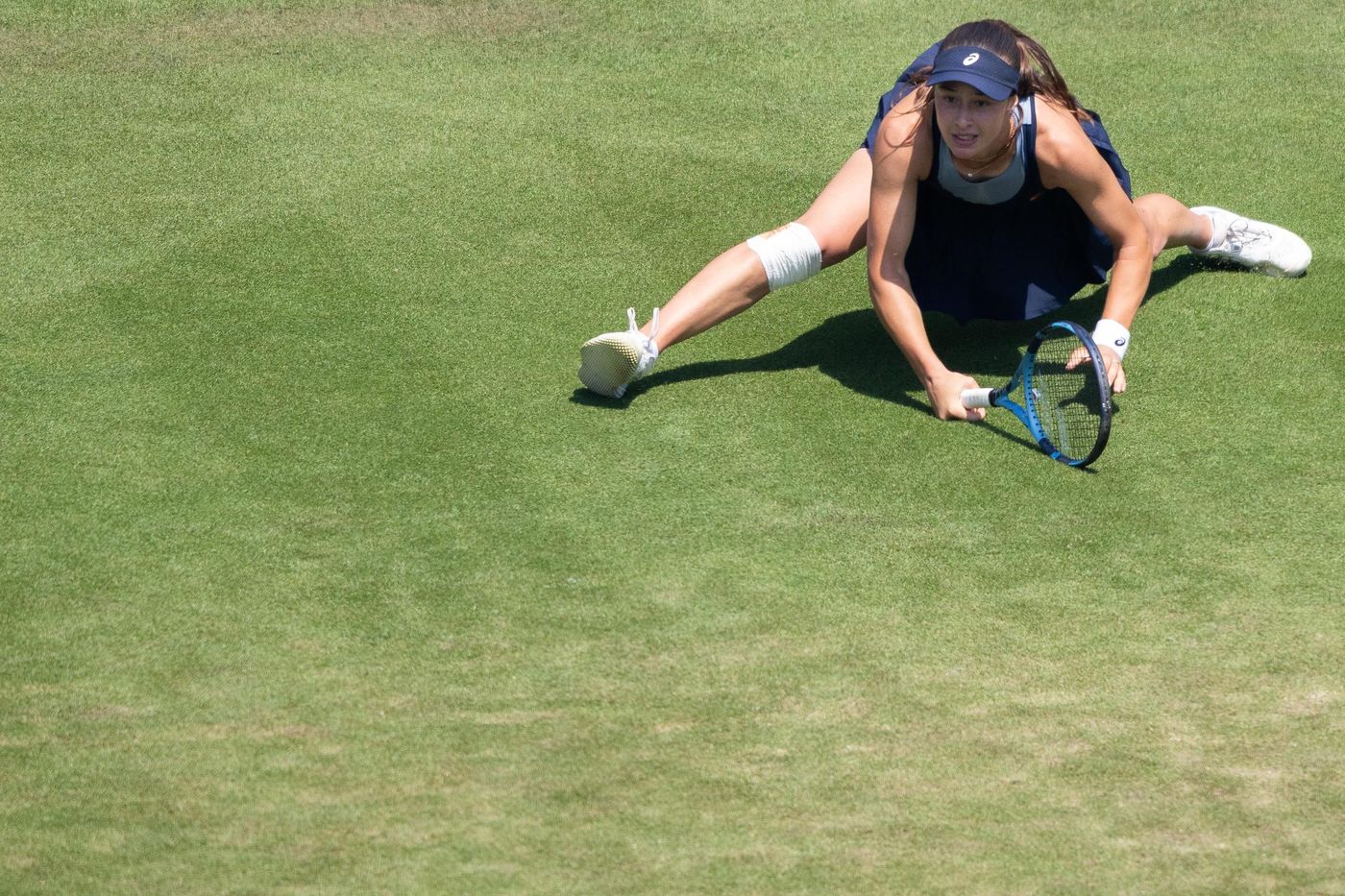 Tennis player sliding for a shot on grass
