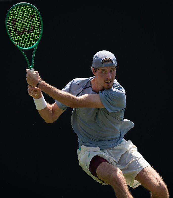 Tennis player mid-forehand against a black backdrop