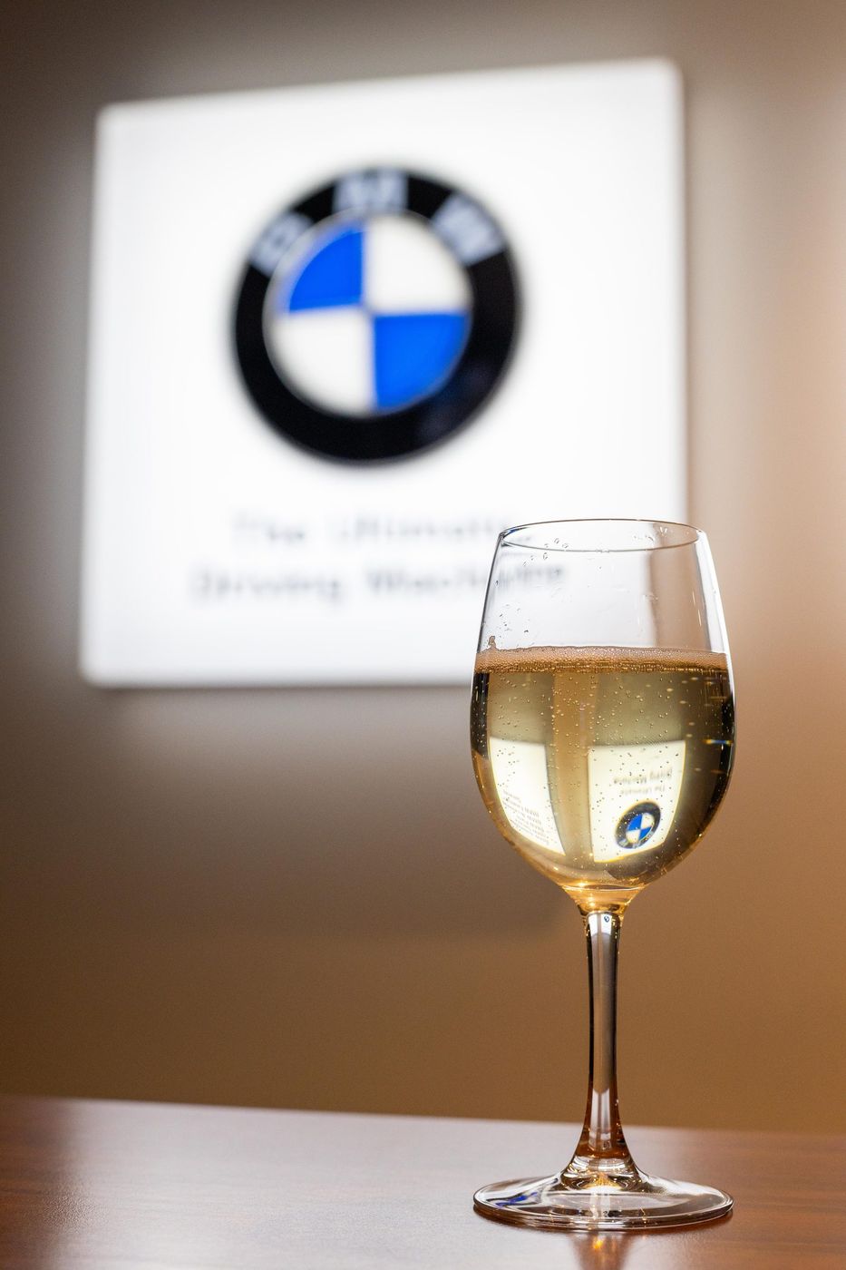 Glass of white wine beside a BMW sign