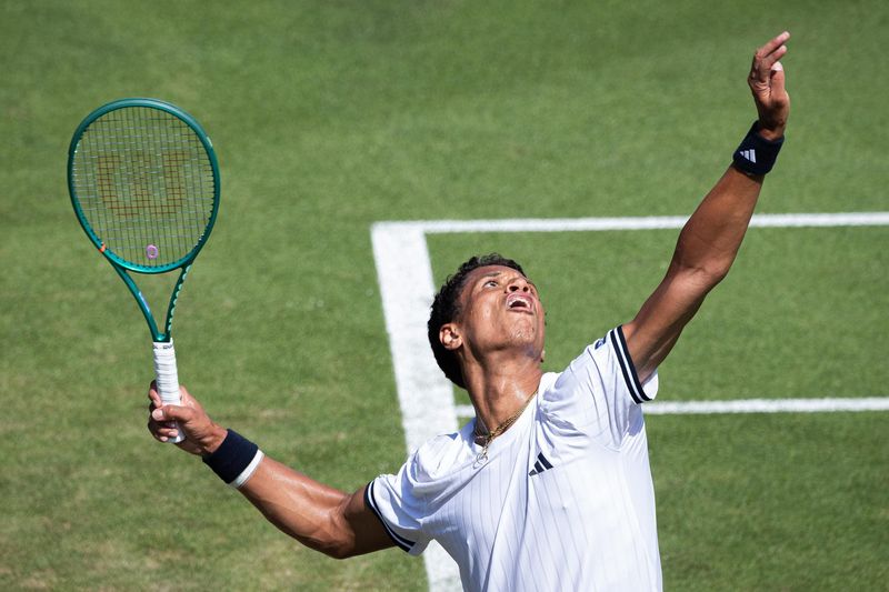 Tennis player serving on a grass court